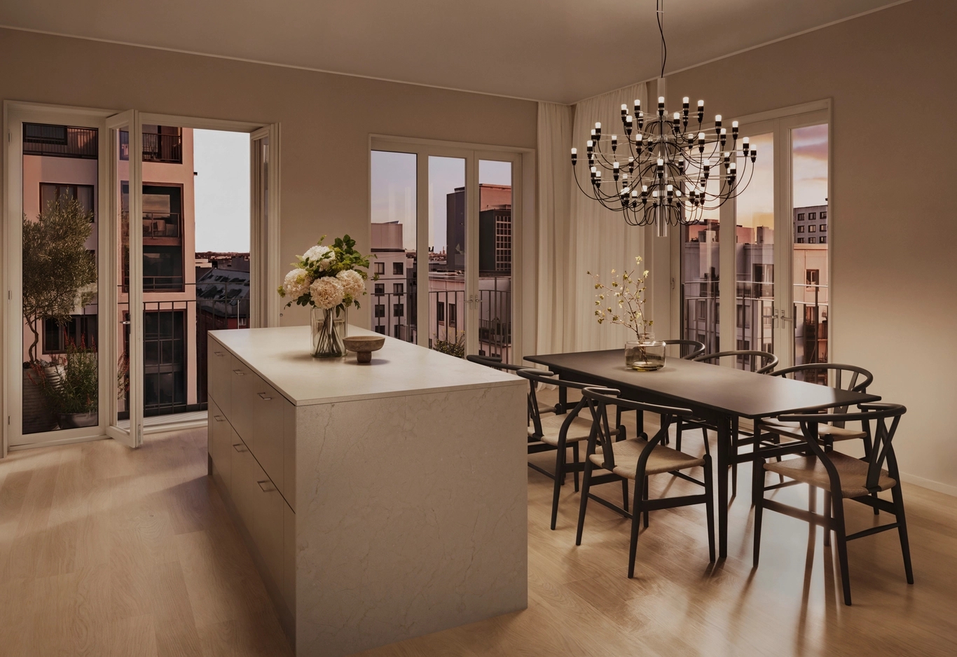 Modernt kök och matplats med en stor köksö, träbord, svarta stolar och en ljuskrona i solnedgången.