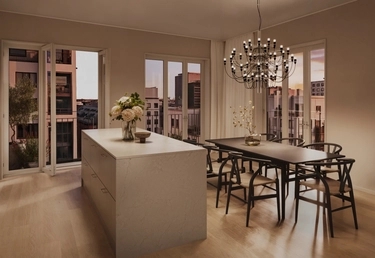 Modernt kök och matplats med en stor köksö, träbord, svarta stolar och en ljuskrona i solnedgången.