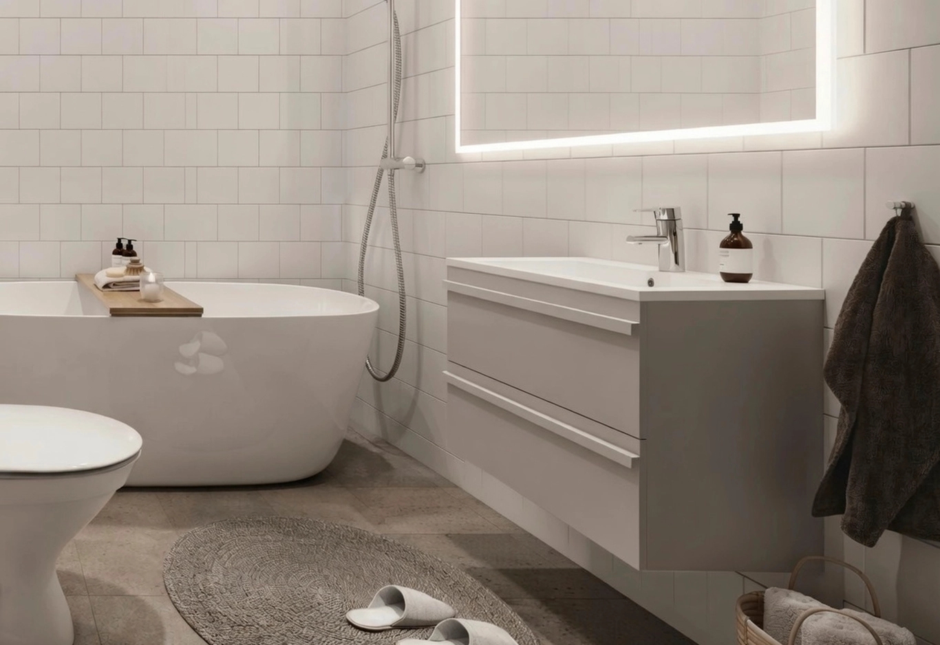 Modernt badrum med fristående badkar, väggmonterat handfat, bakgrundsbelyst spegel och handduk som hänger på väggen.