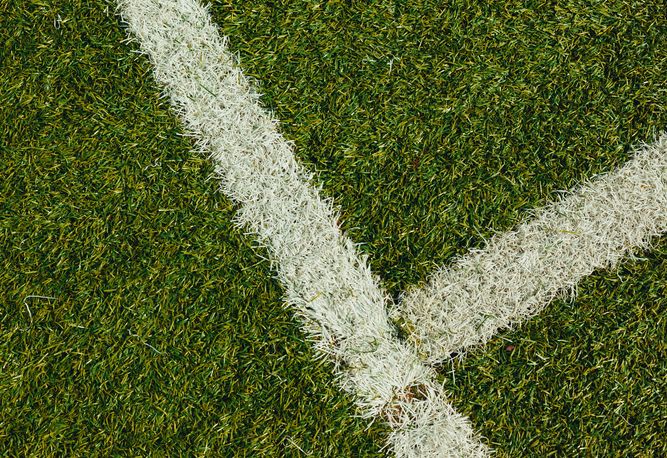 Närbild av konstgräs med två korsande vita linjer som bildar ett hörn.