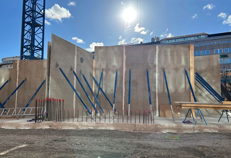Betongväggar med stödjande blå stolpar på en byggarbetsplats. 