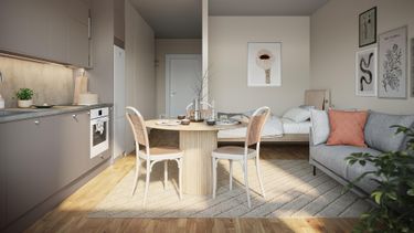 Kompakt studiolägenhet med pentry, matbord för två, säng och en soffa. Ljusa trägolv.