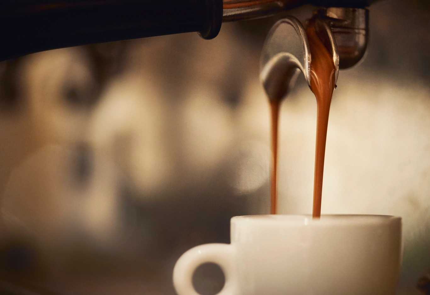 Espressomaskin med flödande espresso ner i en vit espressokopp.