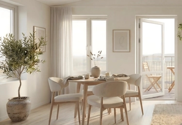 Ljus modern matplats med runt träbord, fyra stolar, stort olivträd och öppen balkongdörr.