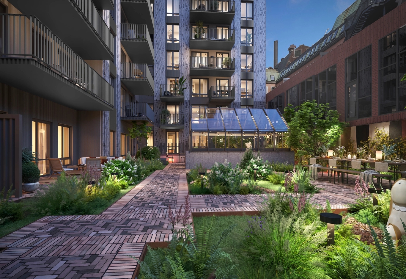 House of Nelly. Modern innergård med grönskande planteringar, tegelgångar, matbord och stora fönster i skymningen.