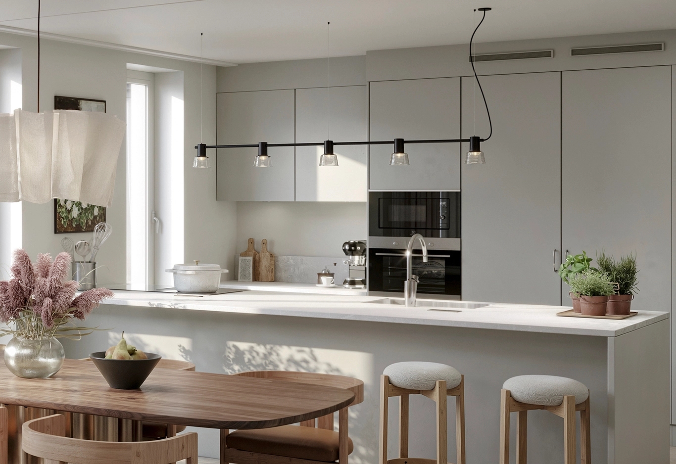 Modernt kök med ljusa skåp, en vit köksö med diskho, barstolar och ett matbord med blommor.