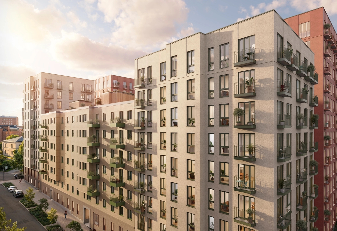 Moderna flerfamiljshus med balkonger, belägna längs en lugn stadsgata under en delvis molnig himmel.