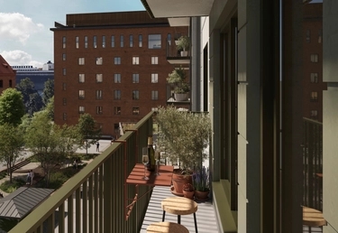 En balkong med bord, stolar och krukväxter har utsikt över en innergård och ett tegelhus med lägenheter.