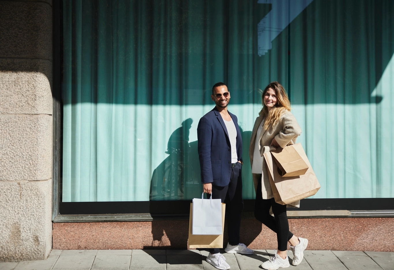 Ett par framför ett skyltfönster med shoppingkassar.