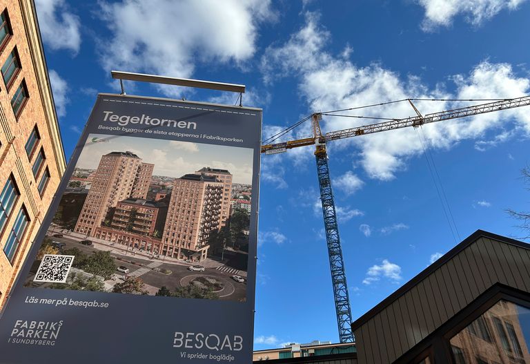 En byggarbetsplats med en hög byggnad på gång bredvid en stor kran. En reklamskylt för "Tegeltornen" visar det färdiga arkitektprojektet.