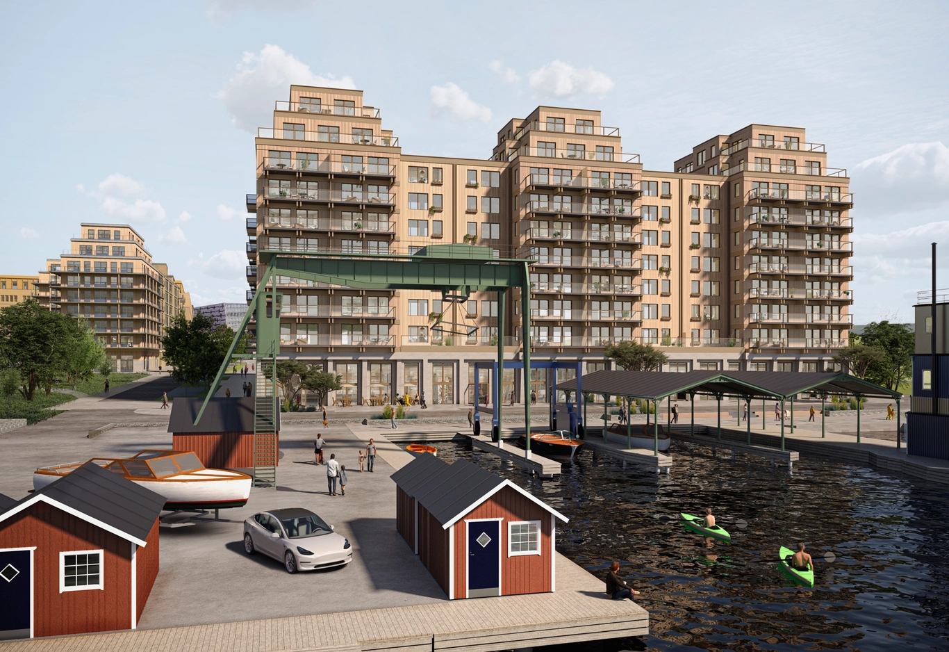 Moderna lägenhetsbyggnader vid en kanal med röda båthus, en grön lyftkran, kajaker och människor.
