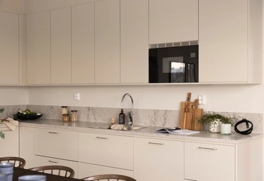 Modernt kök med ljusa skåp, marmorbänkskiva, diskho och olika köksartiklar prydligt arrangerade.