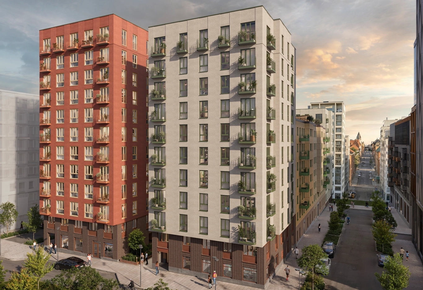 Två moderna flerfamiljshus står mitt emot varandra längs en trädkantad gata i solnedgången.