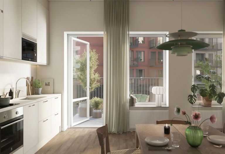Del av kök med matplats och ett dukat bord. En altandörr är öppen.