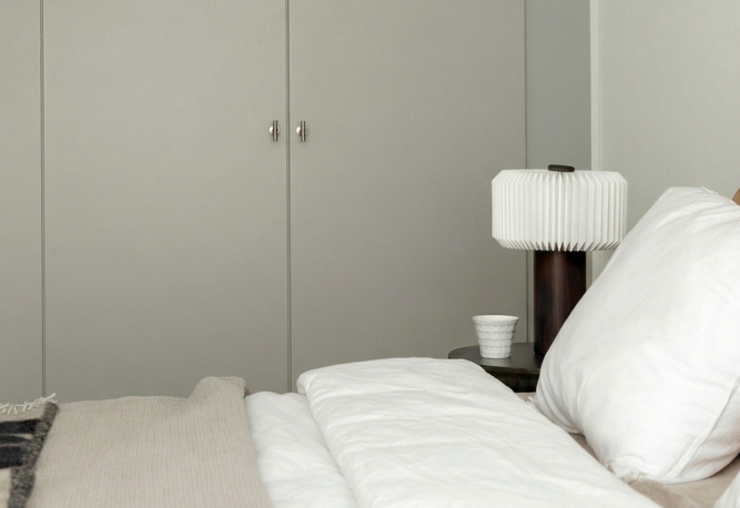 Närbild på en säng i förgrunden och en garderobsvägg i bakgrunden