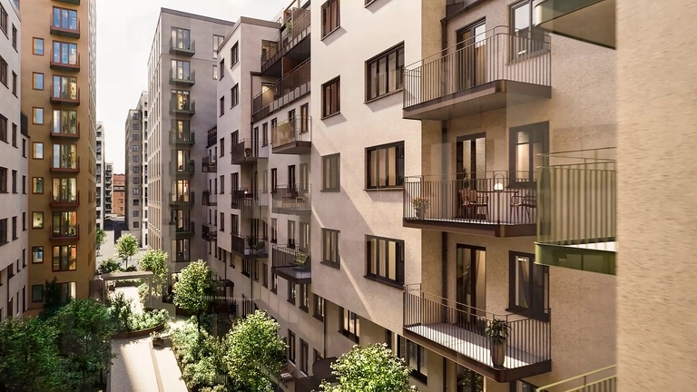 Moderna lägenhetsbyggnader med många balkonger runt en lummig innergård i solsken.