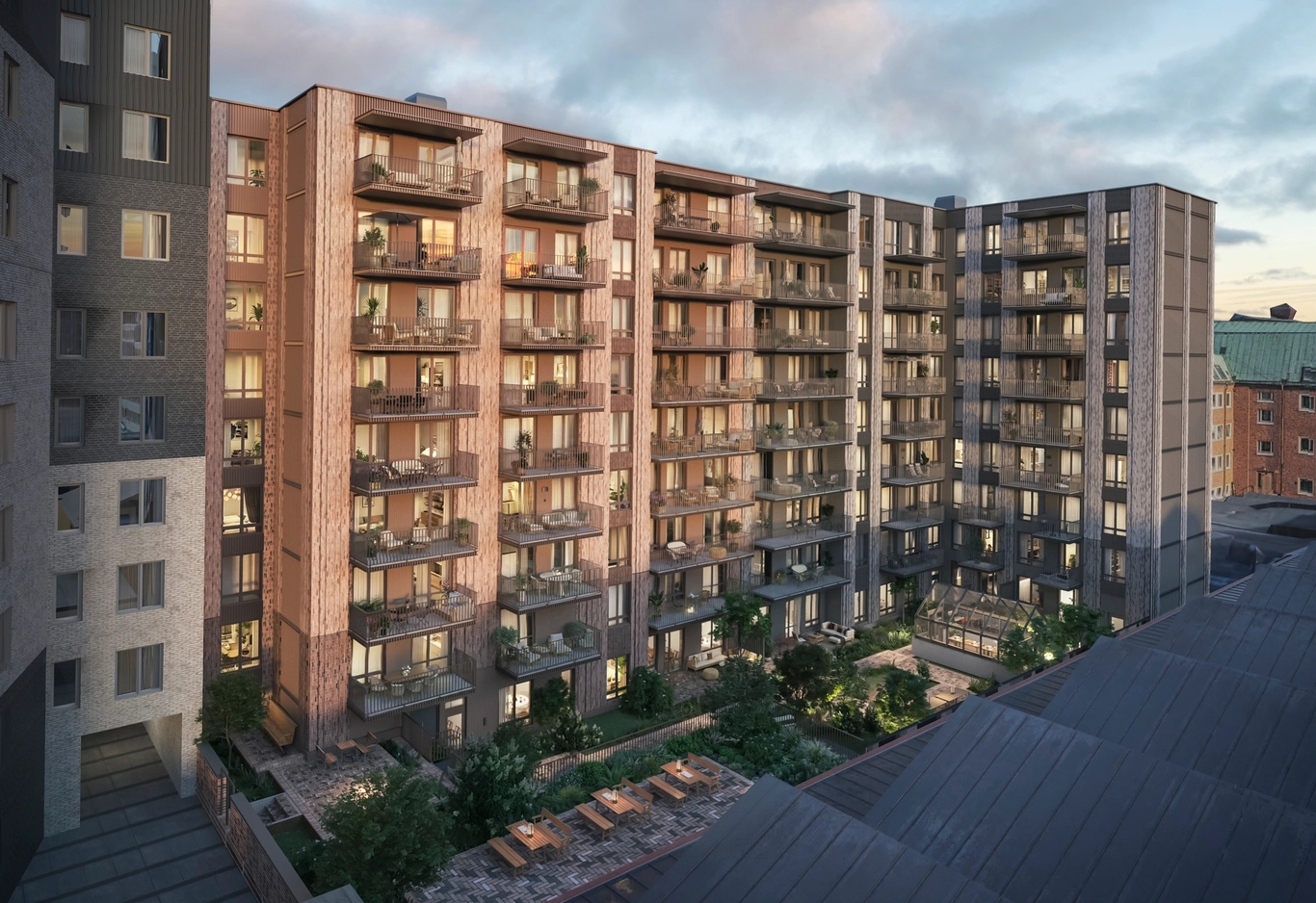 House of Nelly. Ett modernt hyreshus med balkonger som vetter mot en innergård, fotograferat i skymningen.