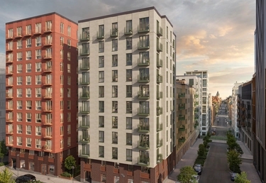 Två moderna flerfamiljshus på en lugn stadsgata med träd och en molnig himmel i bakgrunden.