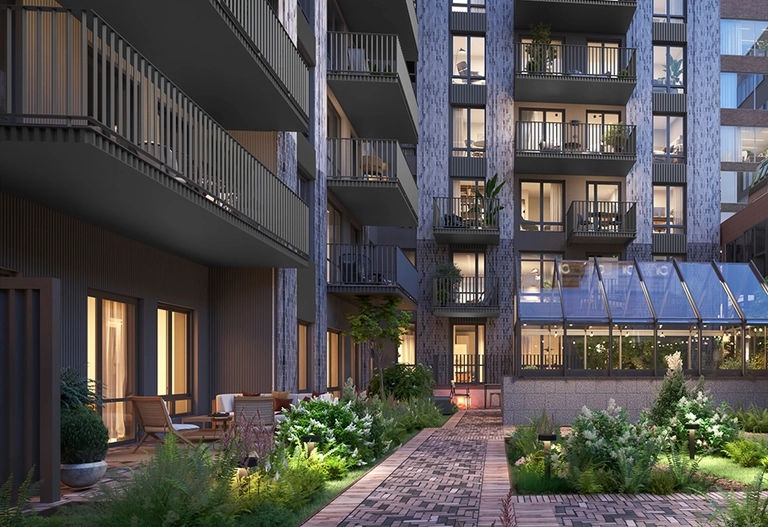 Låst innergård vid House of Nelly men grönska och stensättning. Bilden visar även ett växthus med möblering.