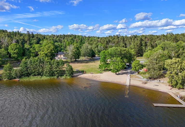 Badplats med sandstrand och brygga.