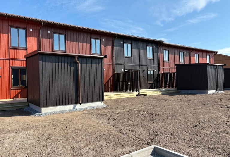 Radhus i olika jordnära kulörer. Altan och förråd syns i framkant.
