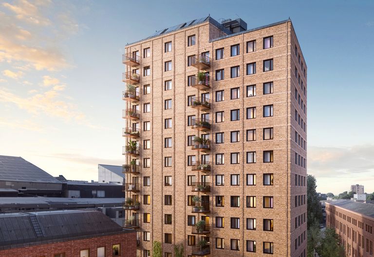 Högt bostadshus med tegelfasad och flera balkonger på ena sidan, mot en klar himmel med några moln.