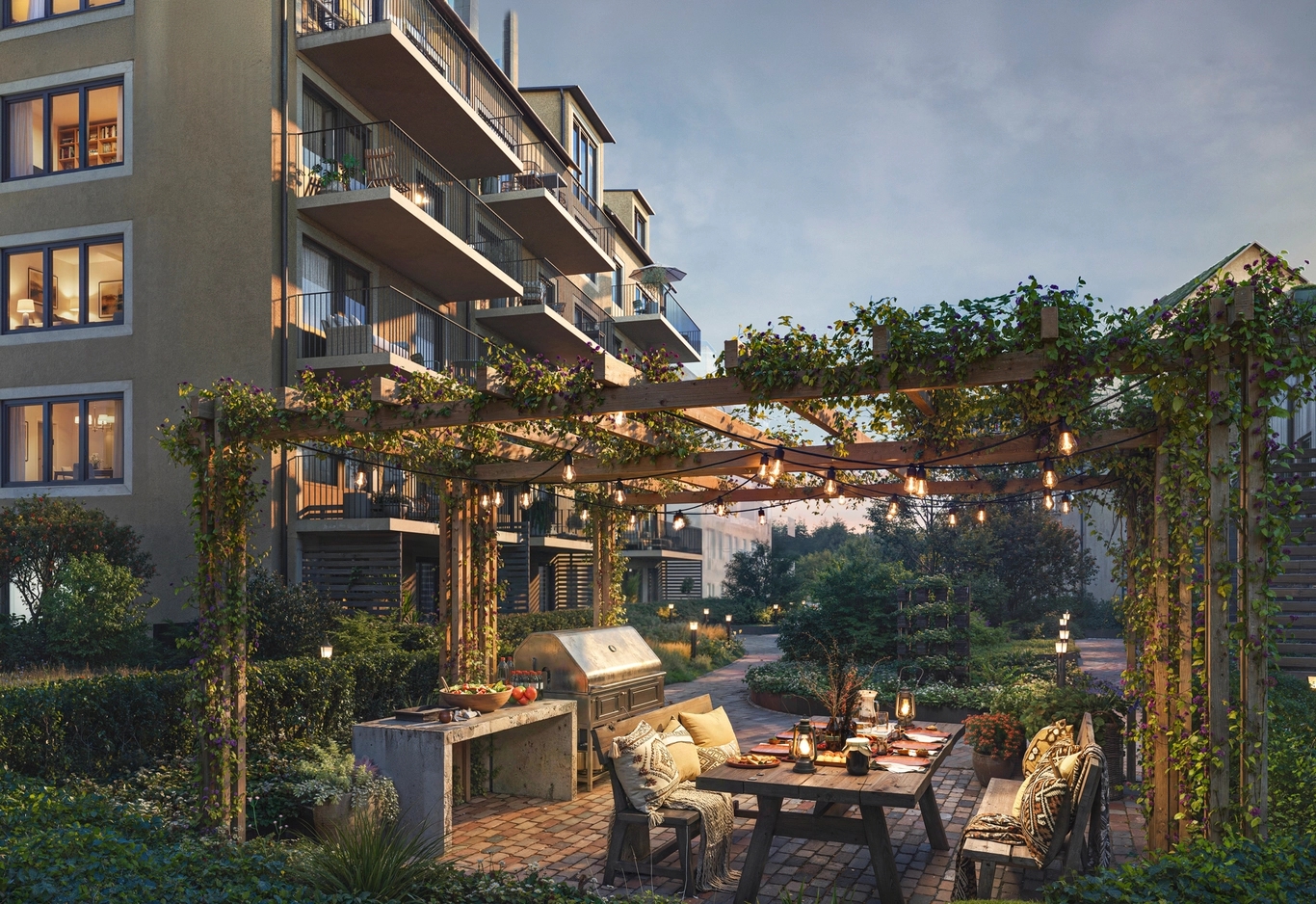 Människor kopplar av på ett gräsbevuxet fält framför bostadshus under en delvis molnig himmel.