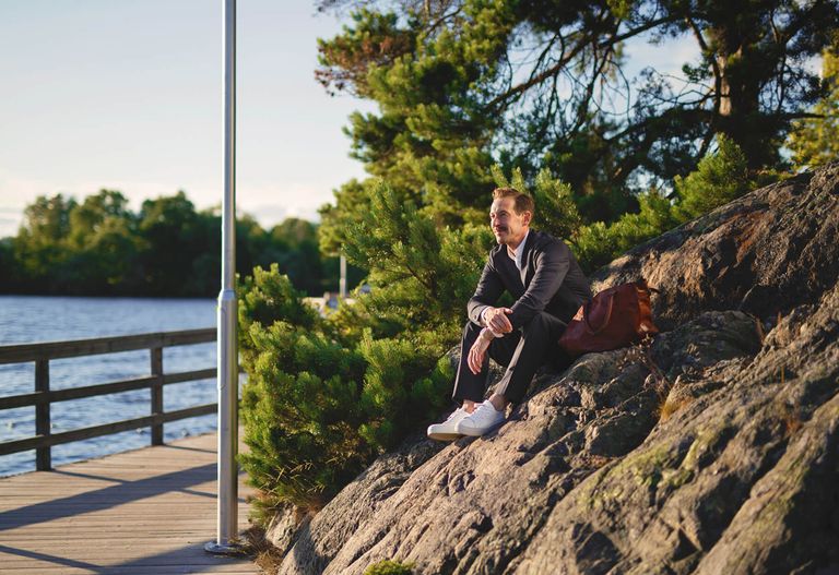 Man som sitter på klipporna invid vattnet och standpromenaden i Hägersten